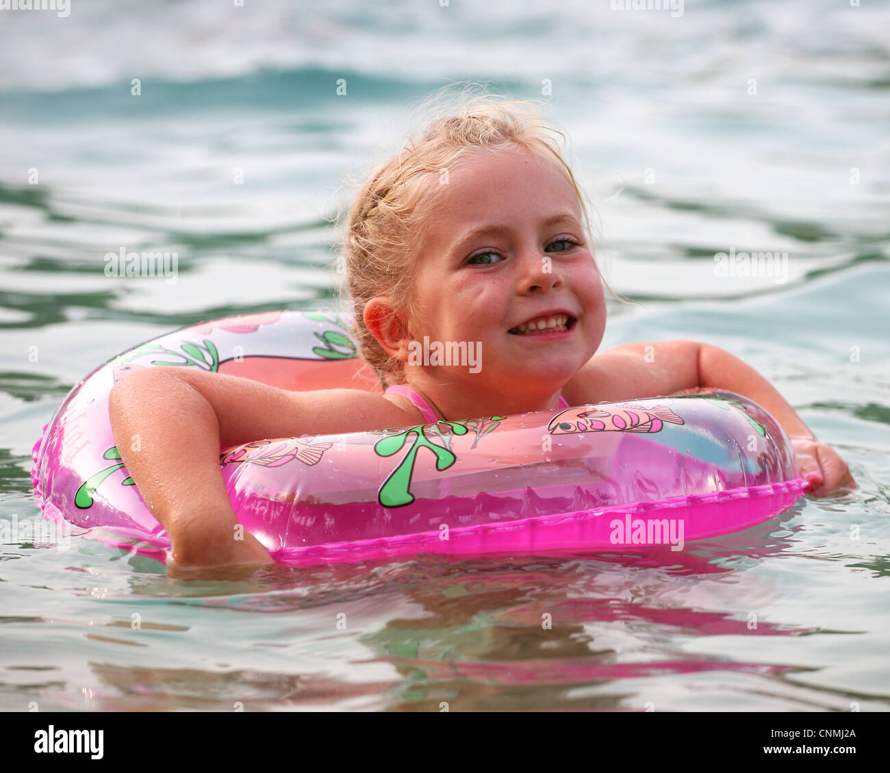 Ein junges Mädchen in einem Pool mit einem rosa Flotation ring Stockfoto
