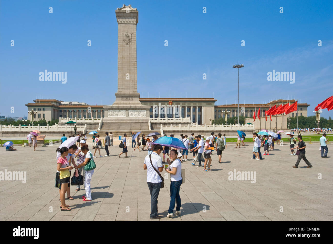 Chinesische Touristen in dem Tiananmen-Platz mit dem Denkmal der Helden und der großen Halle des Volkes in den Hintergrund. Stockfoto