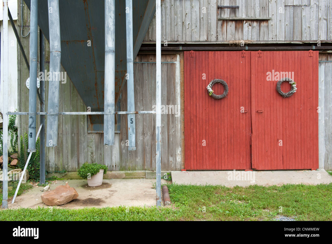 Rote Scheune Türen mit Kränze hängen sie auf einer Scheune neben einem alten Silo Stockfoto
