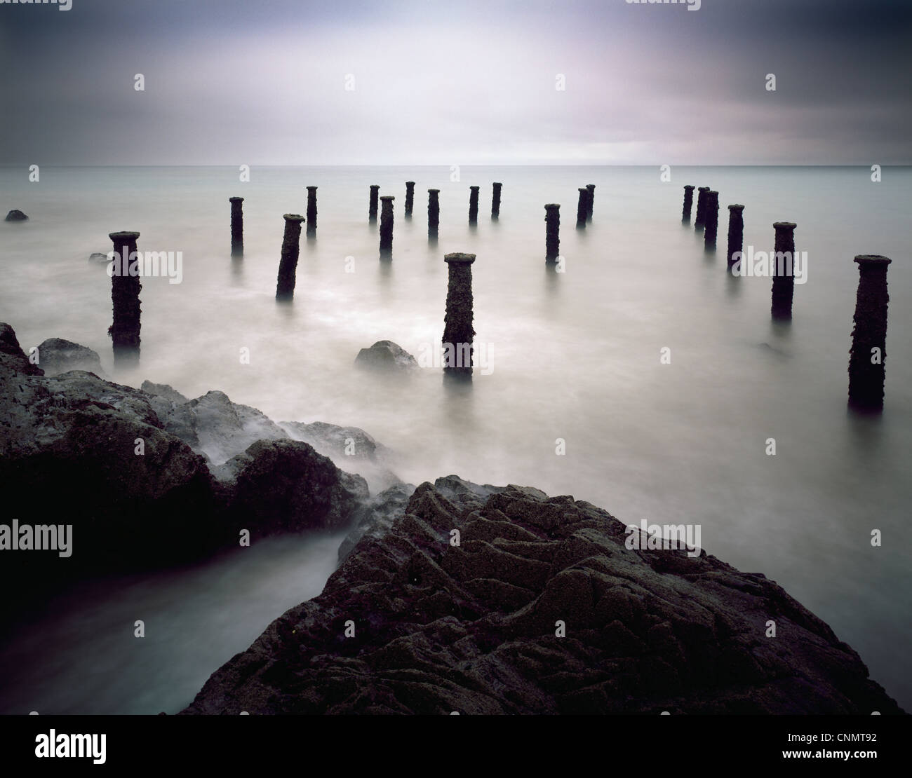 Die Säulen des alten Piers unter einem grauen stürmischen Himmel an Westward Ho! An der Küste von North Devon, England. Stockfoto