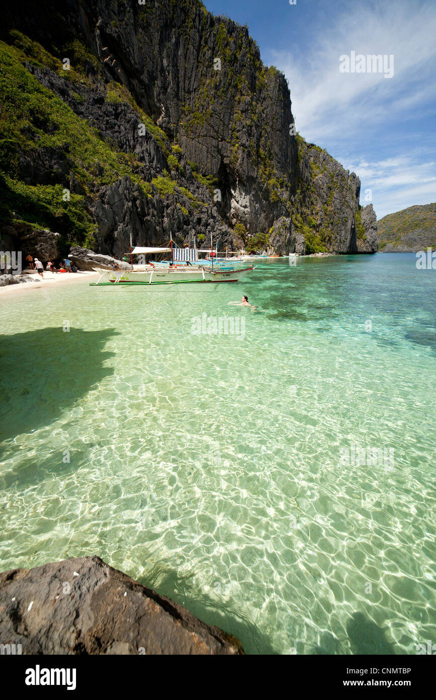 Outrigger Boote in einer kleinen Bucht vor der Küste steil Kalkstein des Tapiutan Island Bacuit Archipels, El Nido, Palawan, Stockfoto