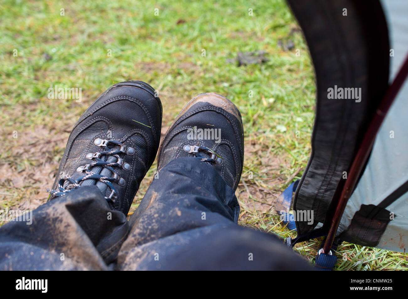 Nassen, schlammigen walking Stiefel und wasserdichte Hose getragen auf der Veranda eines Zeltes auf einem regnerischen Campingurlaub Stockfoto