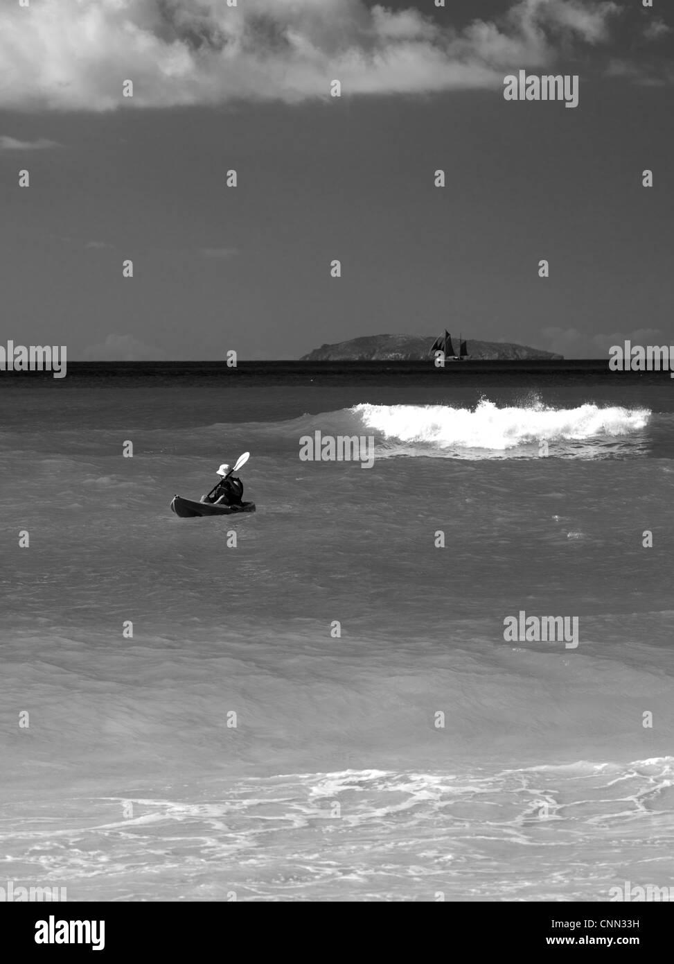 Kajakfahrer & Schwimmer genießen Sie Sonne & Surfen im Cinnamon Bay, St. John's, US Virgin Islands, mit einem großen touristischen Segelboot in der backgr Stockfoto