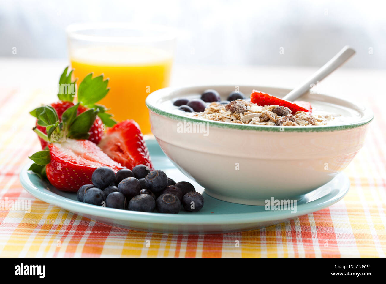 Schüssel mit Müsli mit Joghurt, Erdbeeren und Heidelbeeren, gekochtes Ei und Orangensaft für gesundes Frühstück Stockfoto