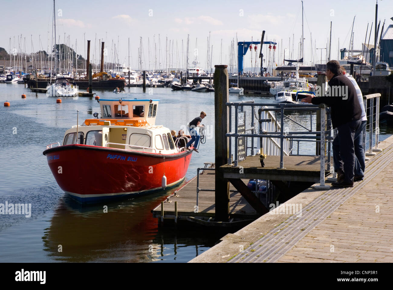 Lymington Hafen - Bootsliegeplatz Reise - junge springt an Land mit Seil - einen entscheidenden Moment - Passanten durch zuschauen Stockfoto