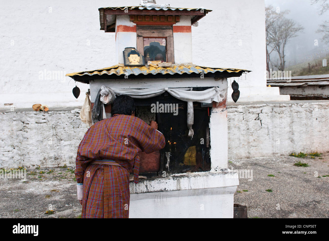 Asien, Bhutan, Dochu La Mann Beleuchtung Yak Butter Kerzen am Heiligtum Stockfoto