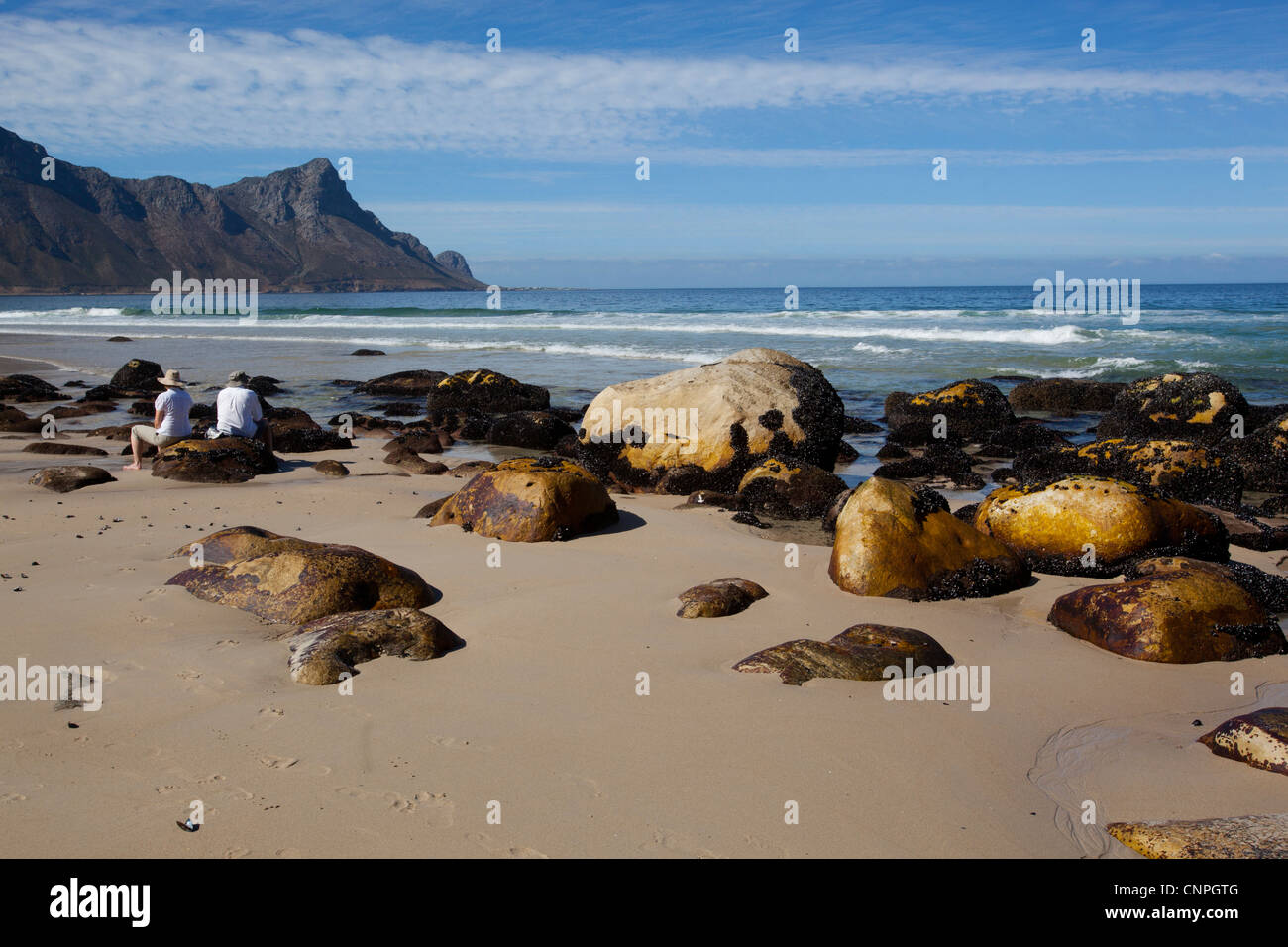 Zwei Menschen sitzen auf den Felsen am Strand, am Kogel Bay, Western Cape, Südafrika Stockfoto