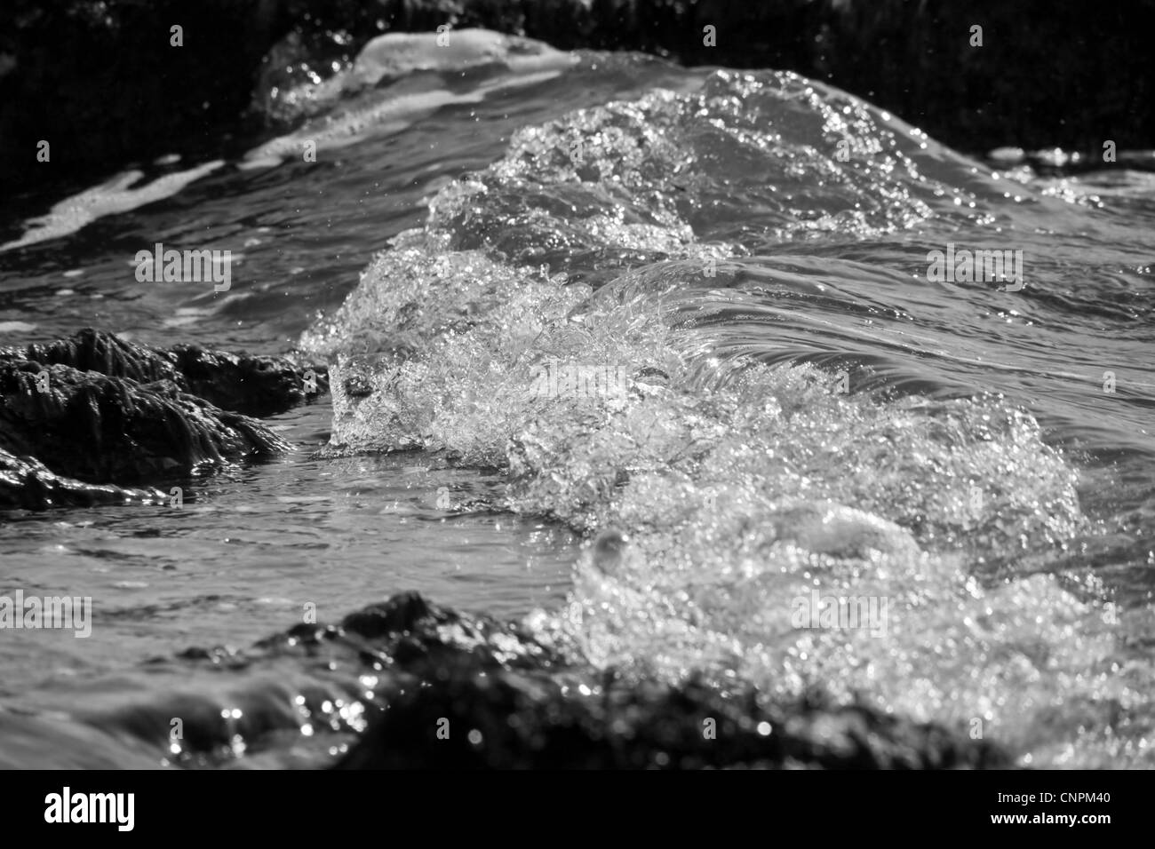 Wellen in Bewegung an der Uferlinie zwischen Felsen brechen. Stockfoto