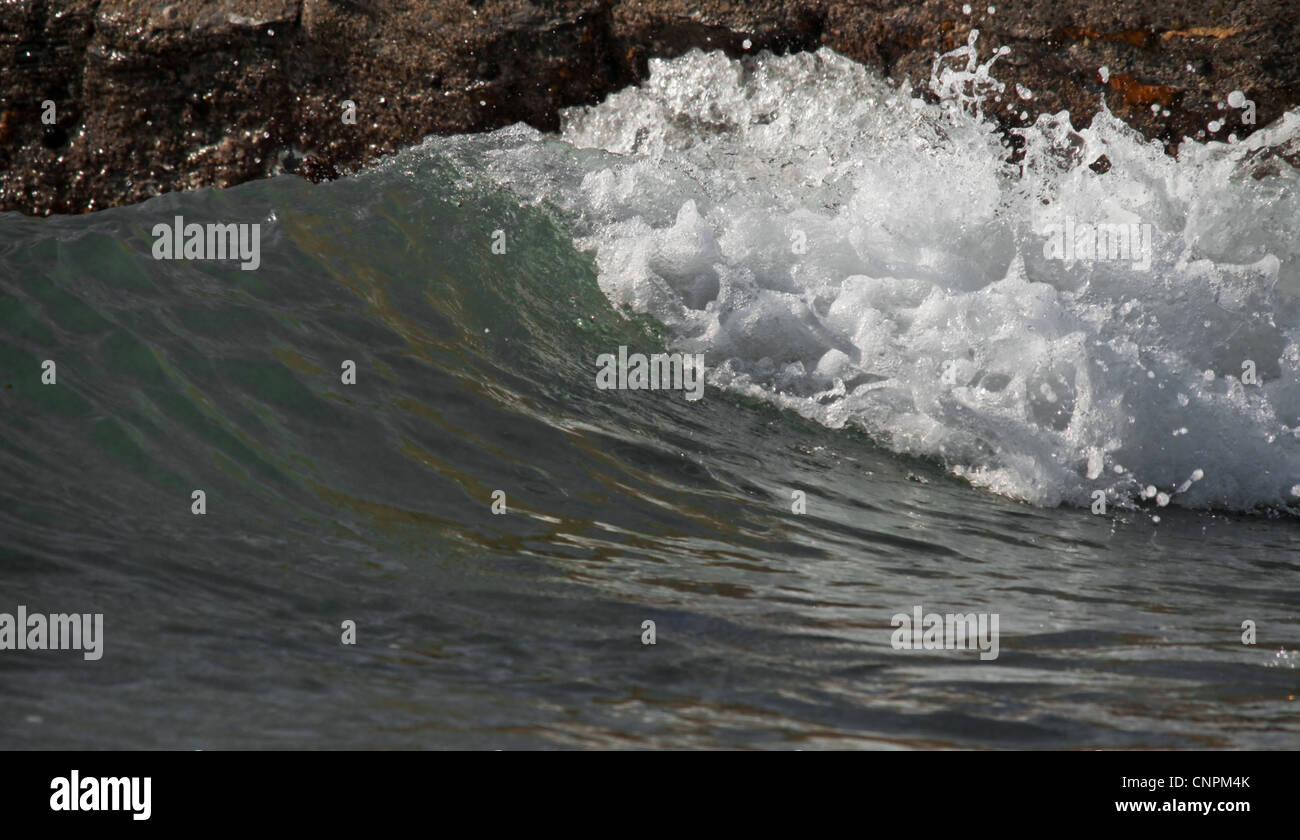Wellen in Bewegung an der Uferlinie zwischen Felsen brechen. Stockfoto