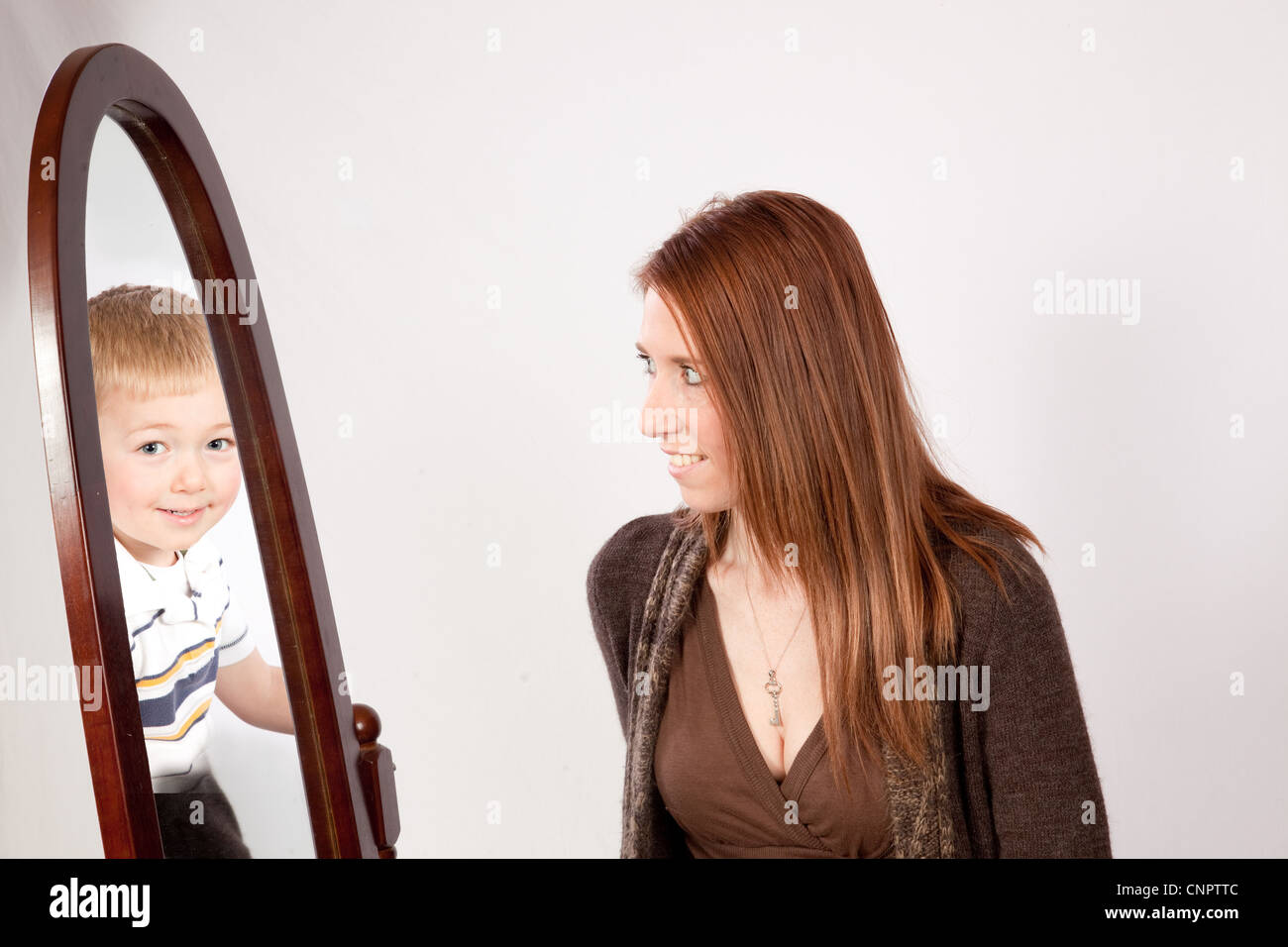 Sehr schön, Mutter in einen Spiegel schauen und sehen ihren blonden Sohn anstatt ihr Bild Stockfoto