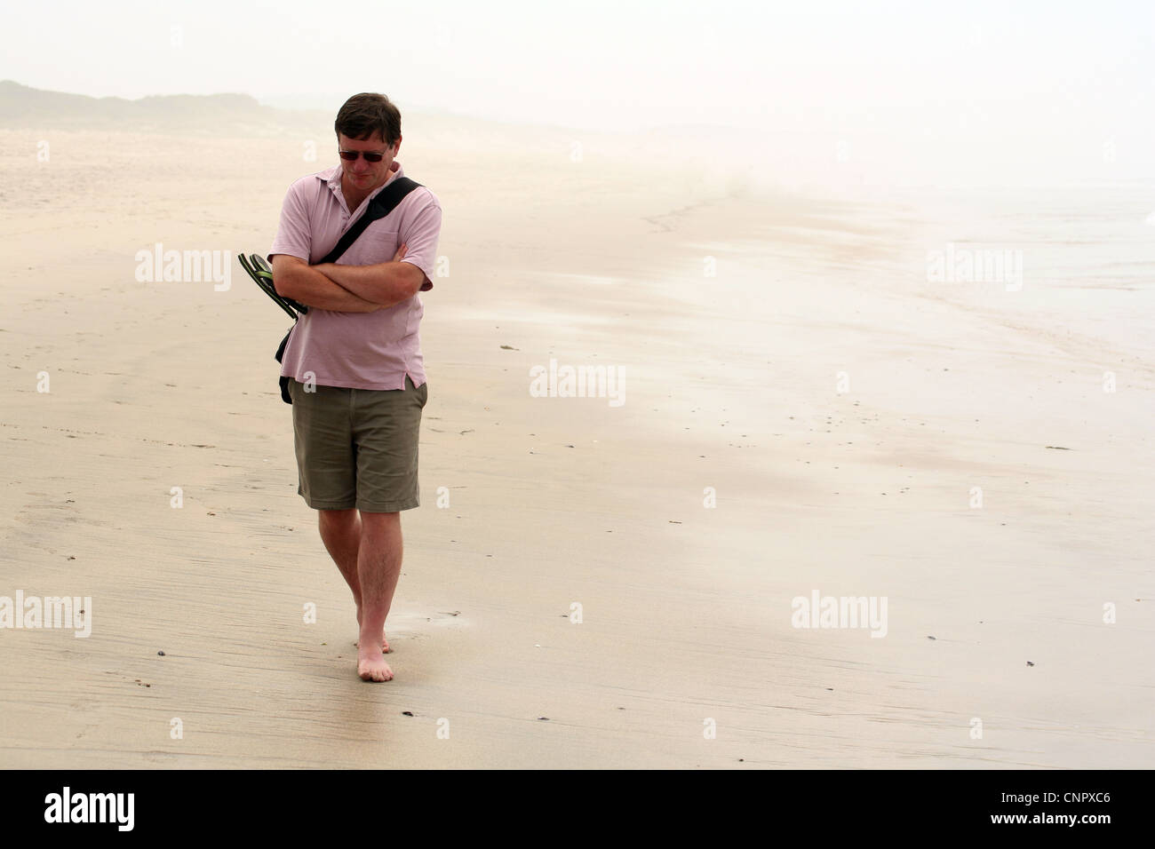 Einsamer Mann mittleren Alters zu Fuß am Strand Suche deprimiert. Stockfoto