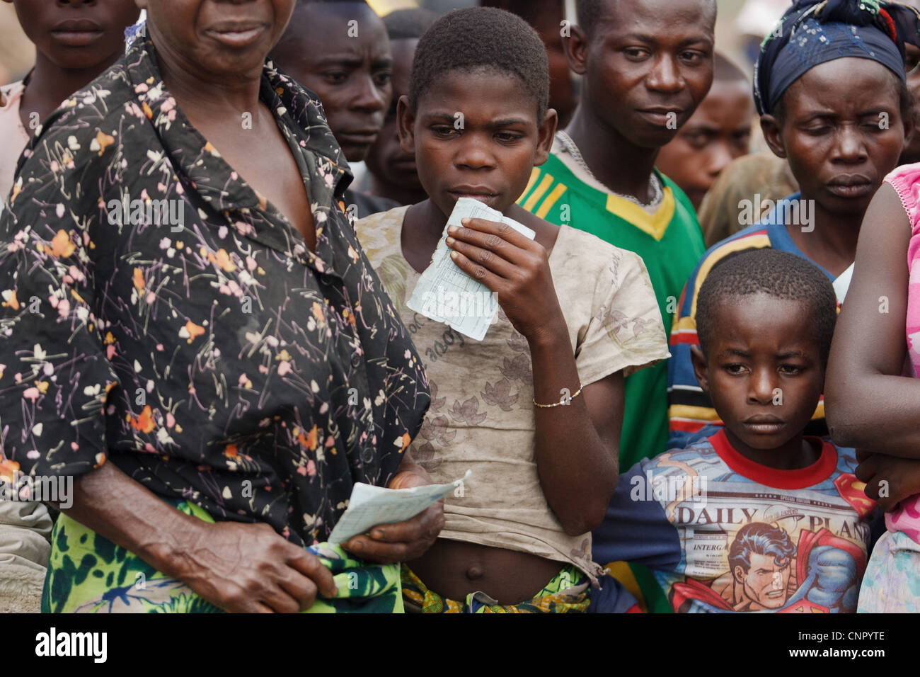 Eine Mädchen hält ein UNHCR ausgestellten Karte Wartezeiten in der Schlange, Gutscheine zu empfangen, während eine non Food-Artikel fair in der Siedlung Miketo IDP, demokratische Republik Kongo Stockfoto