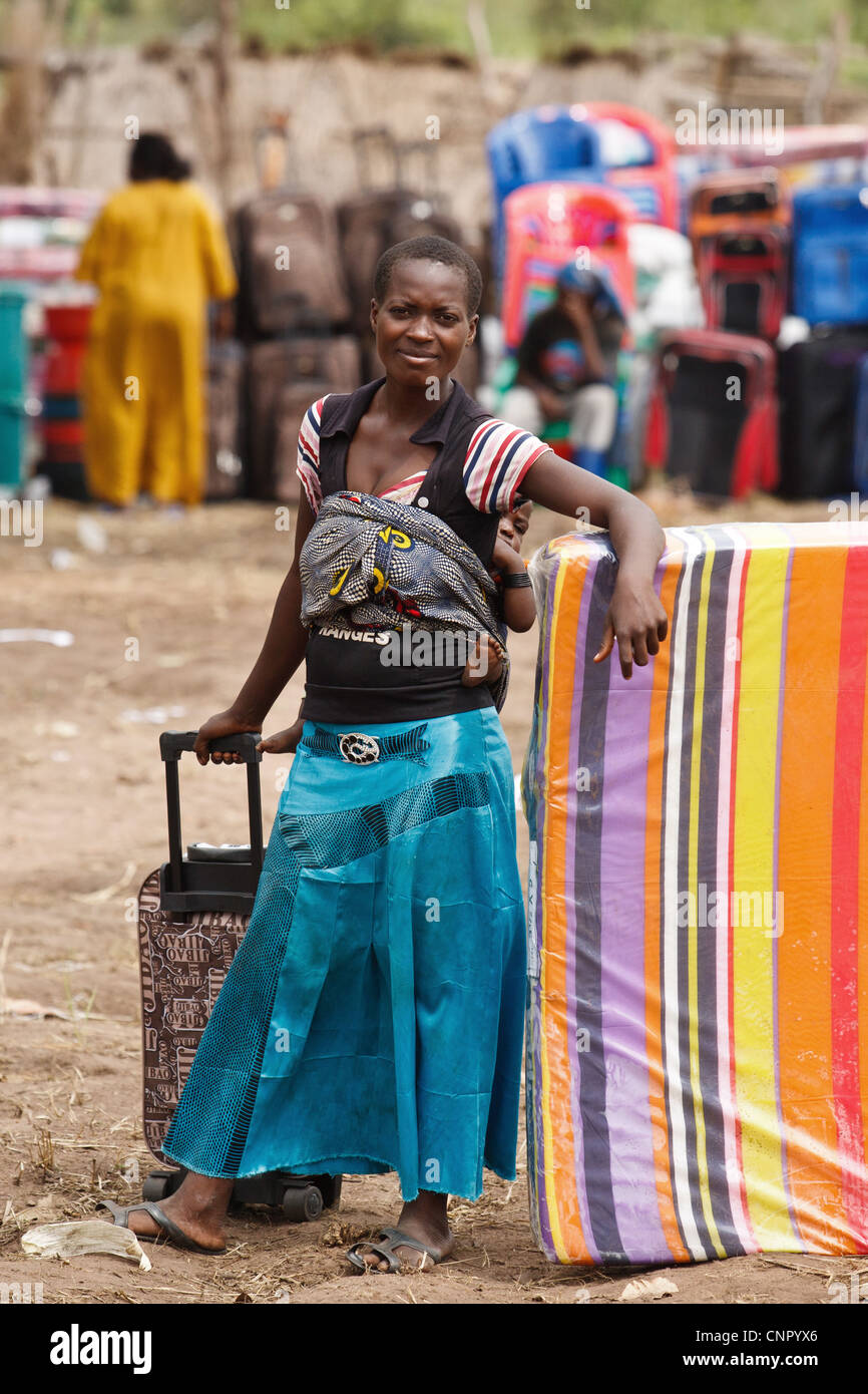 Eine Frau mit einer Matratze und einem Koffer kaufte sie in einem non-Food-Artikel fair in der Siedlung Miketo IDP, Provinz Katanga, demokratische Republik Kongo Stockfoto