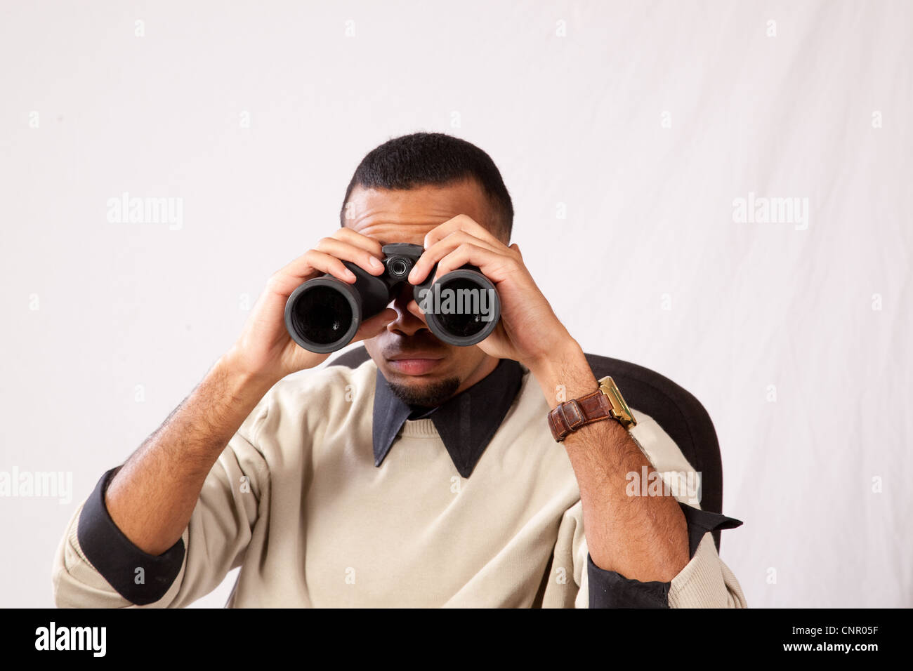 Schwarzer Mann mit einem Fernglas, Ausspionieren von jemand Stockfoto