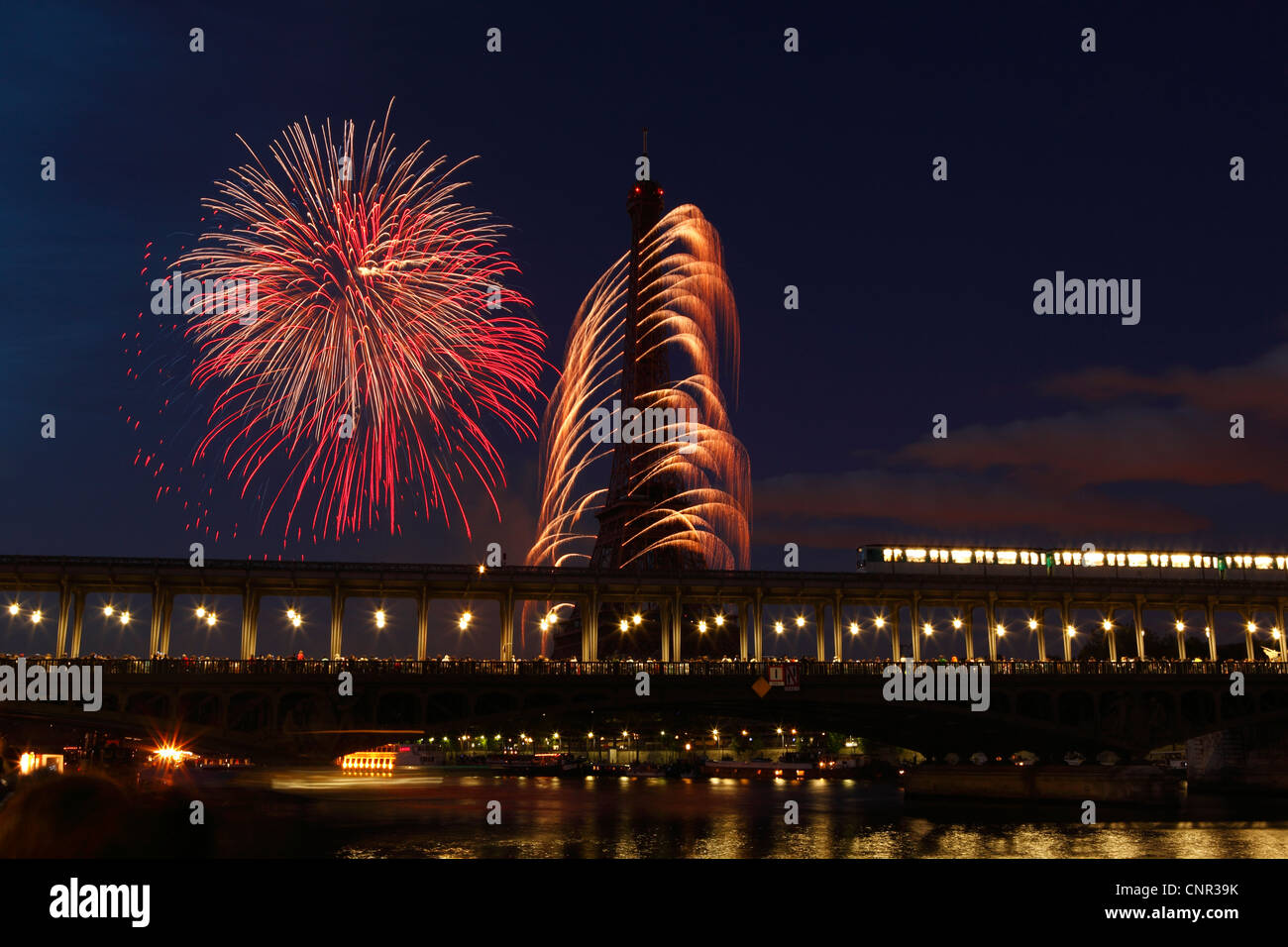 Parisern und Touristen beobachten Bastille Day Feuerwerk rund um den Eiffelturm mit Passy Brücke im Vordergrund in Paris, Frankreich. Stockfoto