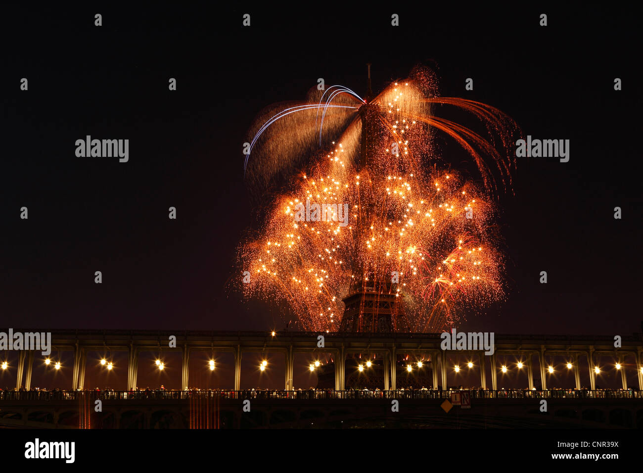 Parisern und Touristen beobachten Bastille Day Feuerwerk rund um den Eiffelturm mit Passy Brücke im Vordergrund in Paris, Frankreich. Stockfoto