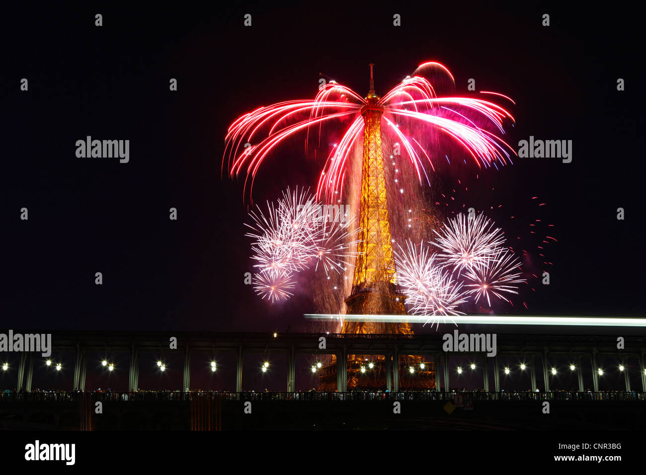 Parisern und Touristen beobachten Bastille Day Feuerwerk rund um den Eiffelturm mit Passy Brücke im Vordergrund in Paris, Frankreich. Stockfoto