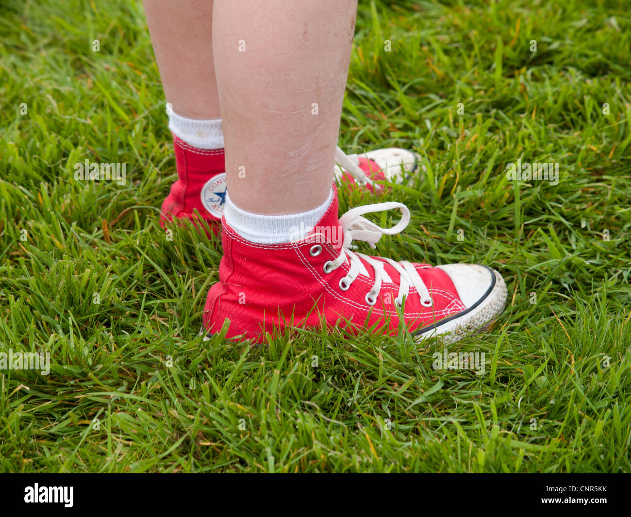 Mädchens Füße im roten Canvas Stiefel stehen auf dem Rasen Stockfoto