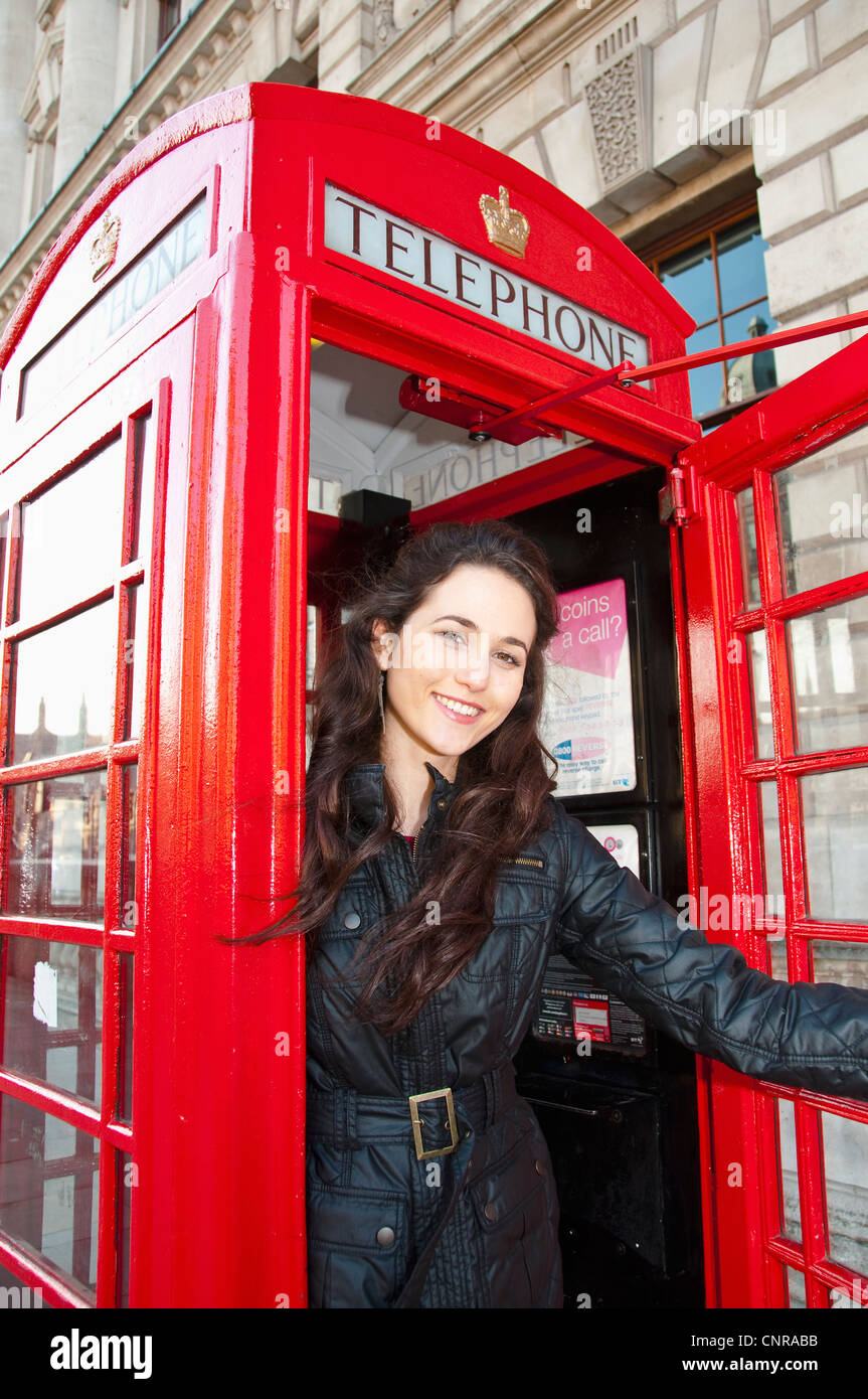 In rote Telefonzelle lächelnde Frau Stockfoto