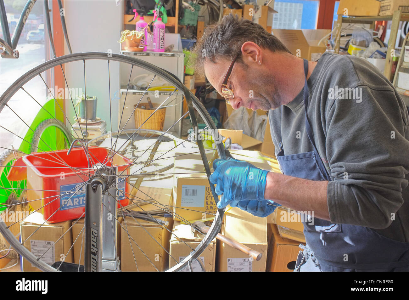 Ein Mechaniker repariert ein Rad in seiner Fahrradreparaturwerkstatt in Penryn, Cornwall, UK Stockfoto