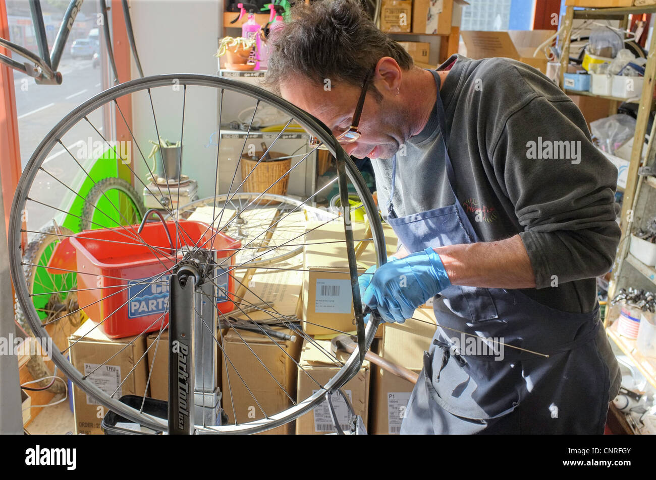 Ein Mechaniker repariert ein Rad in seiner Fahrradreparaturwerkstatt in Penryn, Cornwall, UK Stockfoto