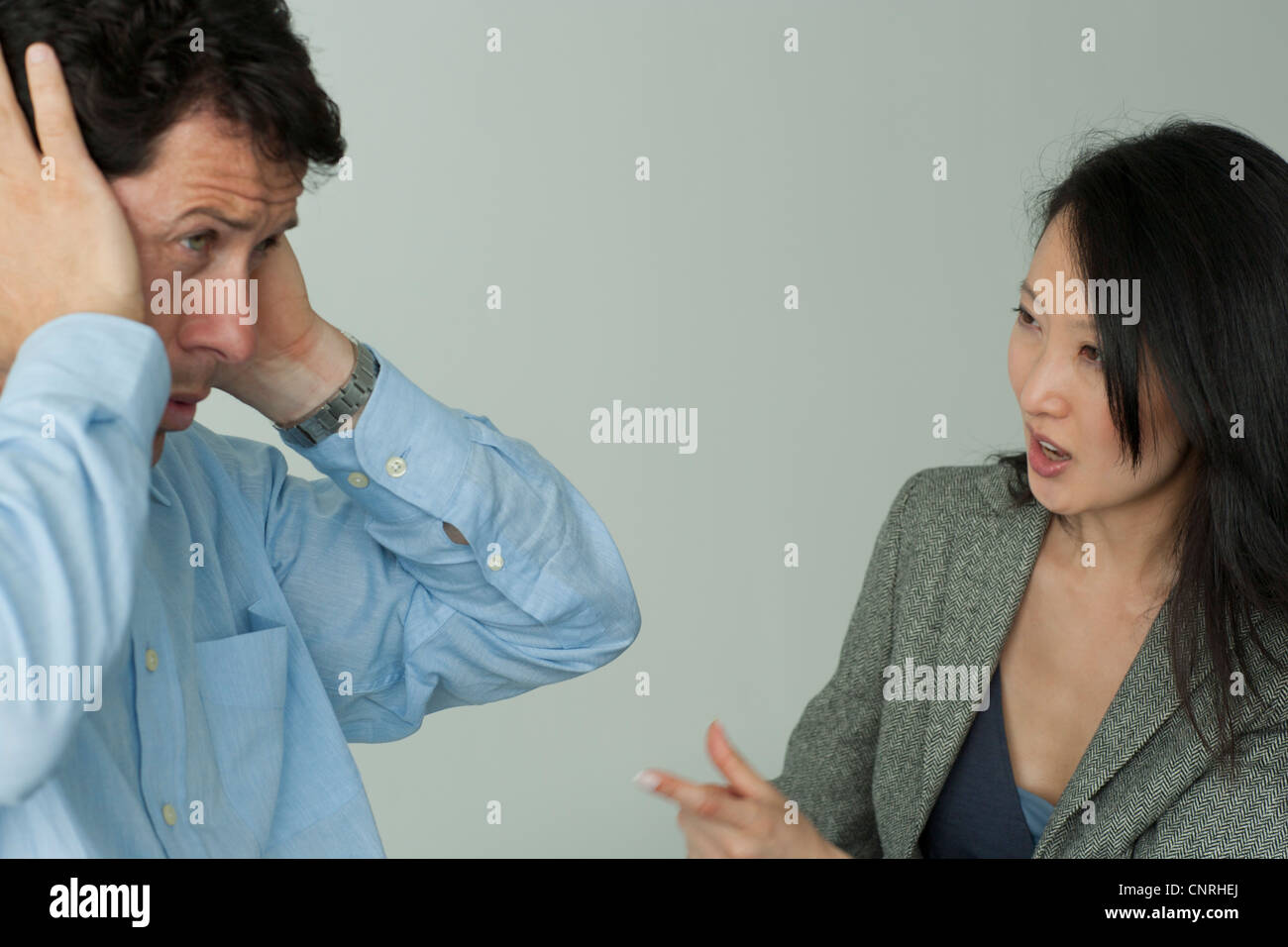 Mann und Frau streiten, Manndeckung seine Ohren mit Händen Stockfoto