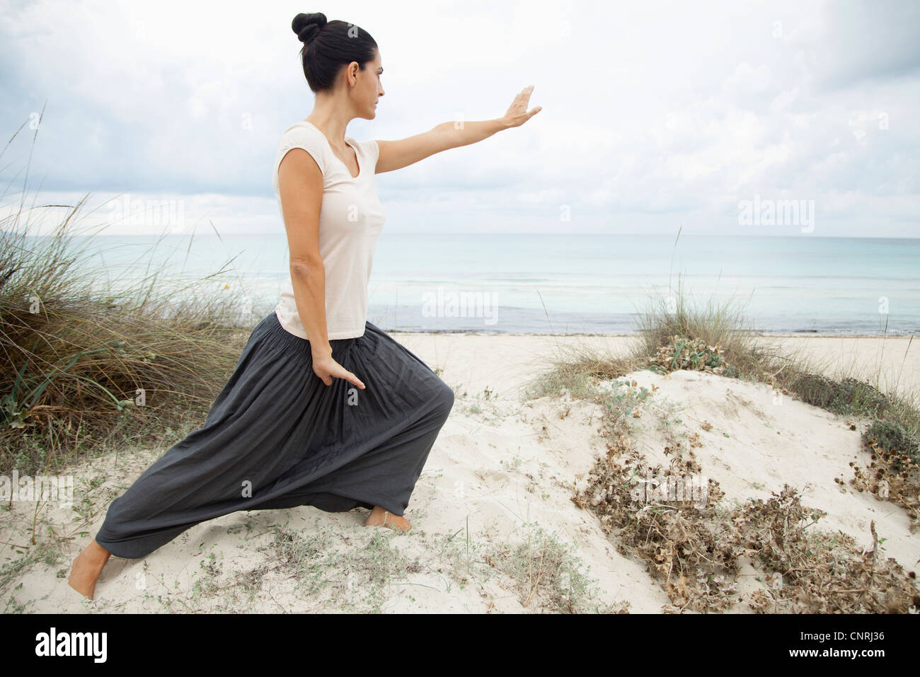 Frau praktizieren Tai Chi Chuan am Strand, Seitenansicht Stockfoto