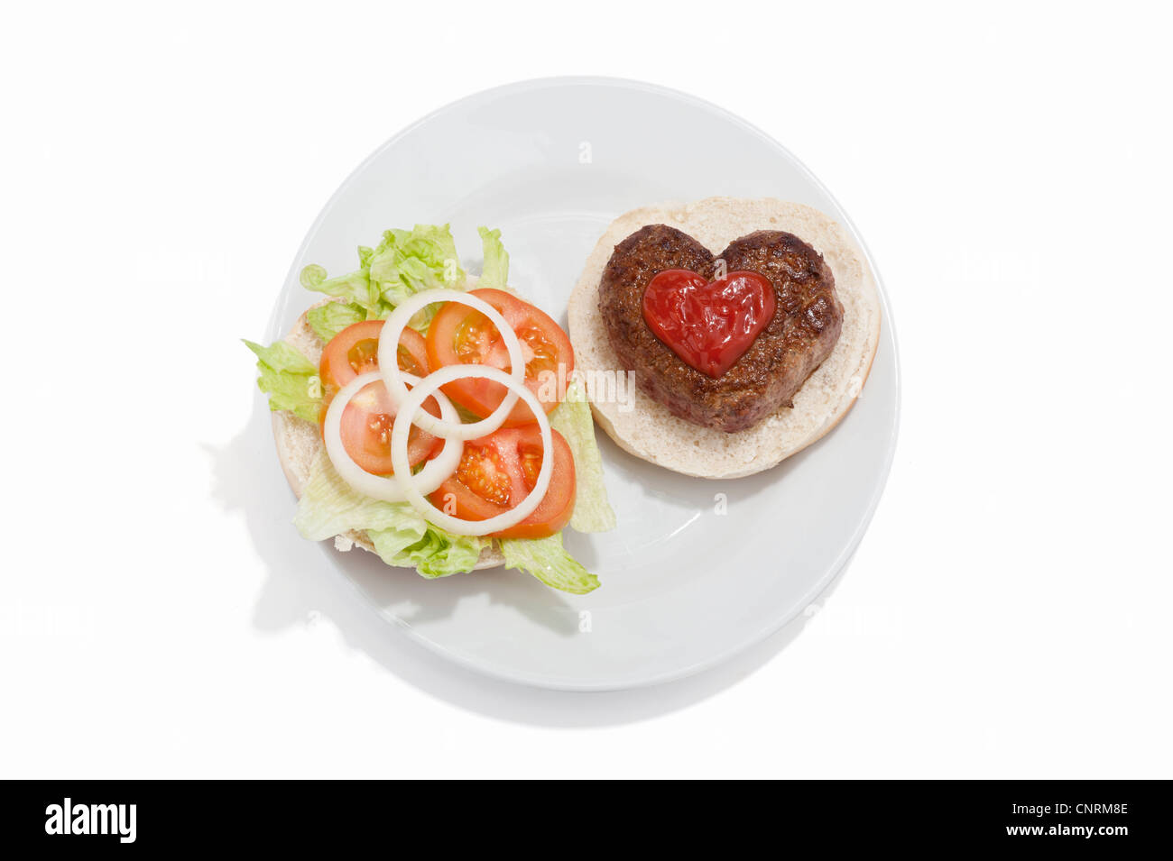Eine herzförmige Beef-Burger auf einem Brötchen mit Tomatensauce und einem Beilagensalat Stockfoto