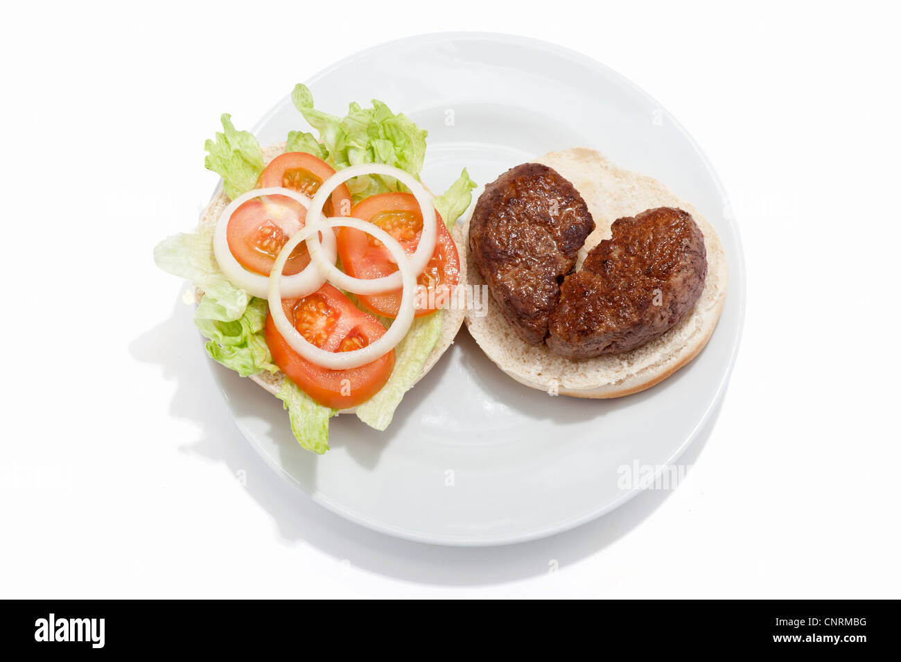 Ein gebrochenes Herz geformt Beef-Burger auf einem Brötchen mit Tomatensauce und einem Beilagensalat Stockfoto