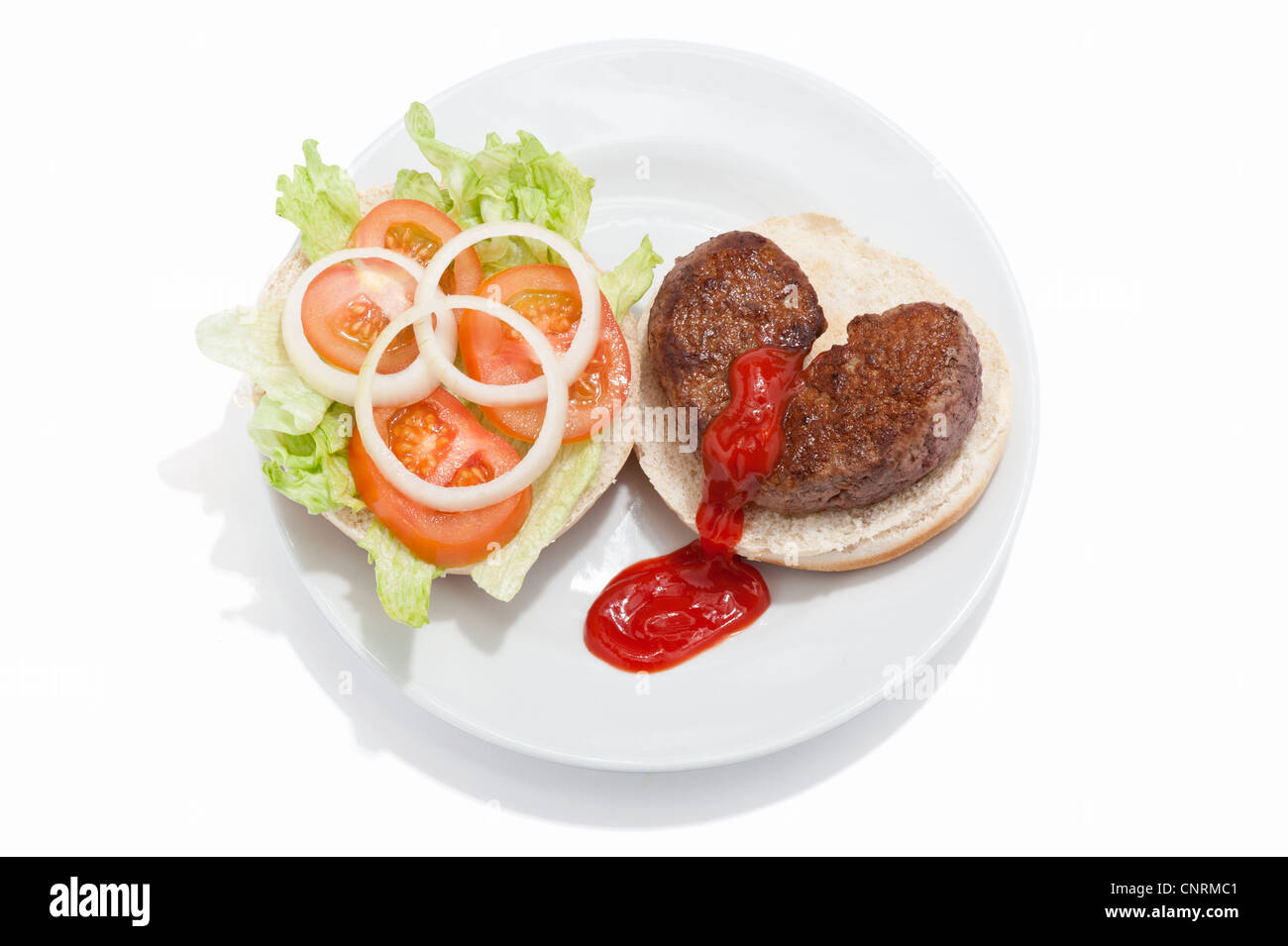 Ein gebrochenes Herz geformt Beef-Burger auf einem Brötchen mit Salat und Tomate Soße Nässen aus es Stockfoto