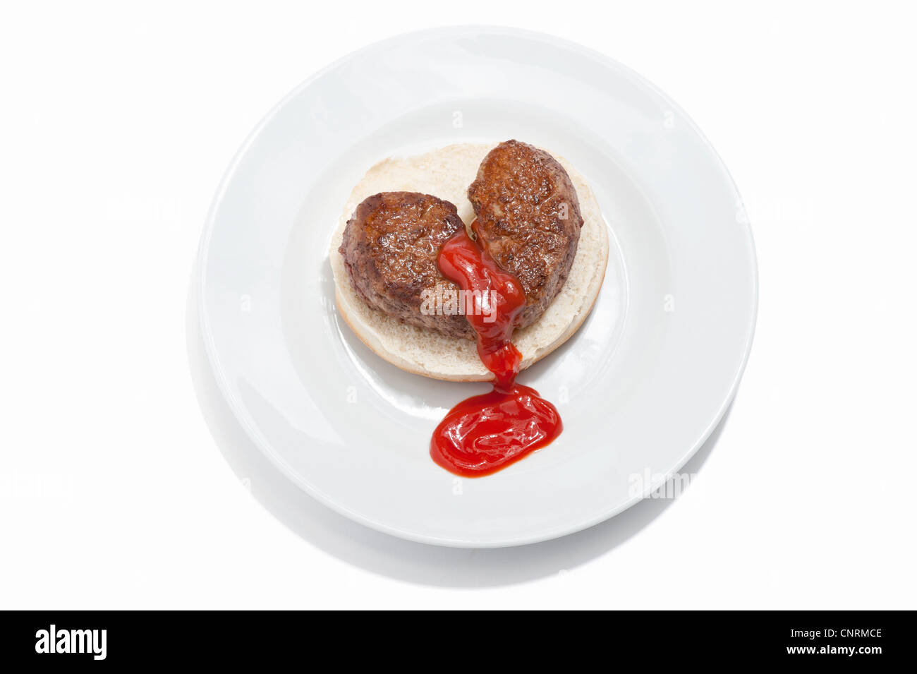 Ein gebrochenes Herz geformt Beef-Burger auf einem Brötchen mit Tomatensauce Nässen aus es Stockfoto