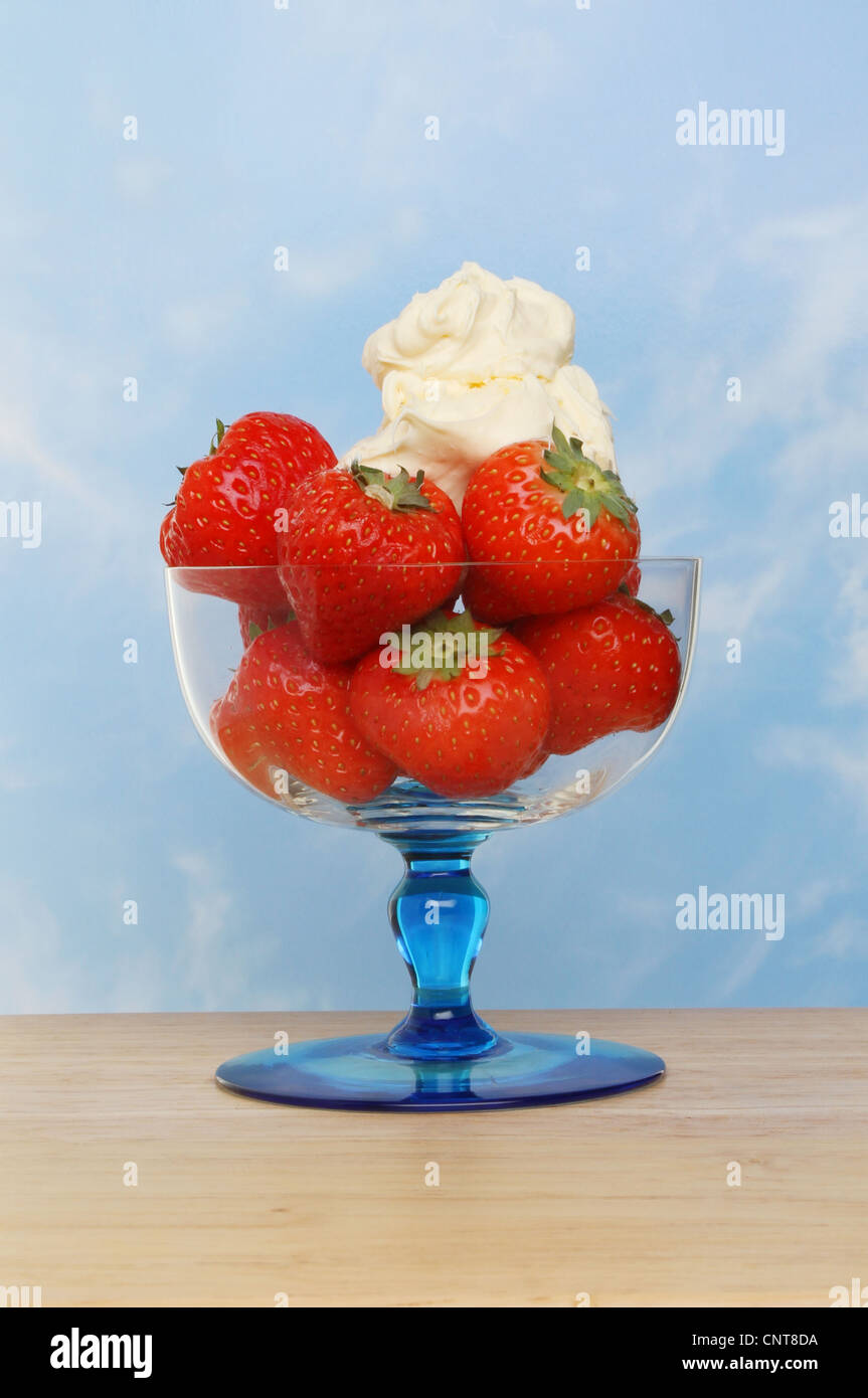 Erdbeeren und Cornish Clotted Cream in einem Eisbecher Glas auf eine Holzoberfläche vor blauem Himmel Stockfoto