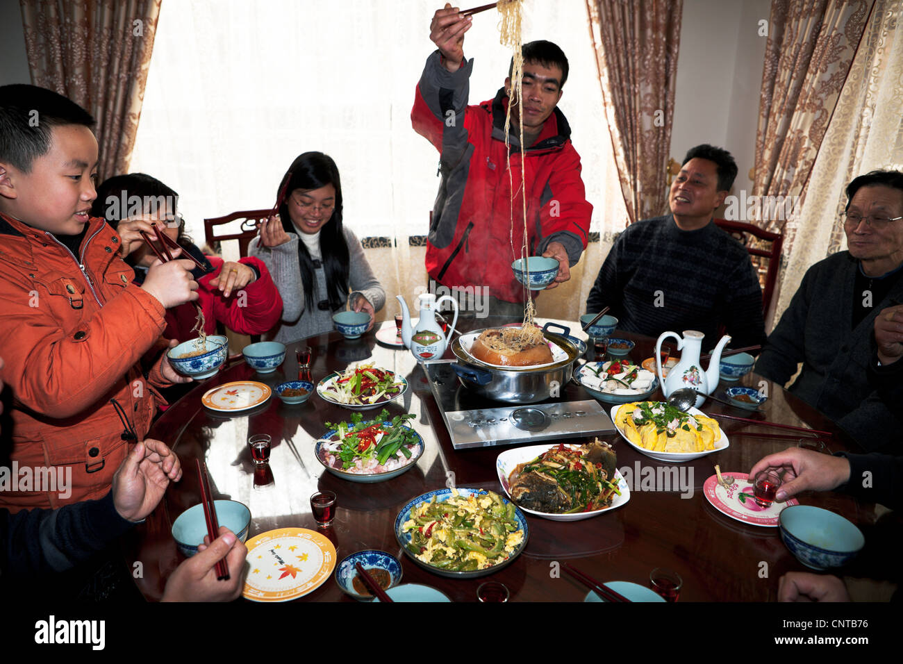China, chinesisches Essen, Familientreffen, süße Jungs, Erwachsene, häusliches Leben, chinesisches Essen, Spaß, Genuss, Esstisch, Winter, Urlaub, rot, Haus Stockfoto