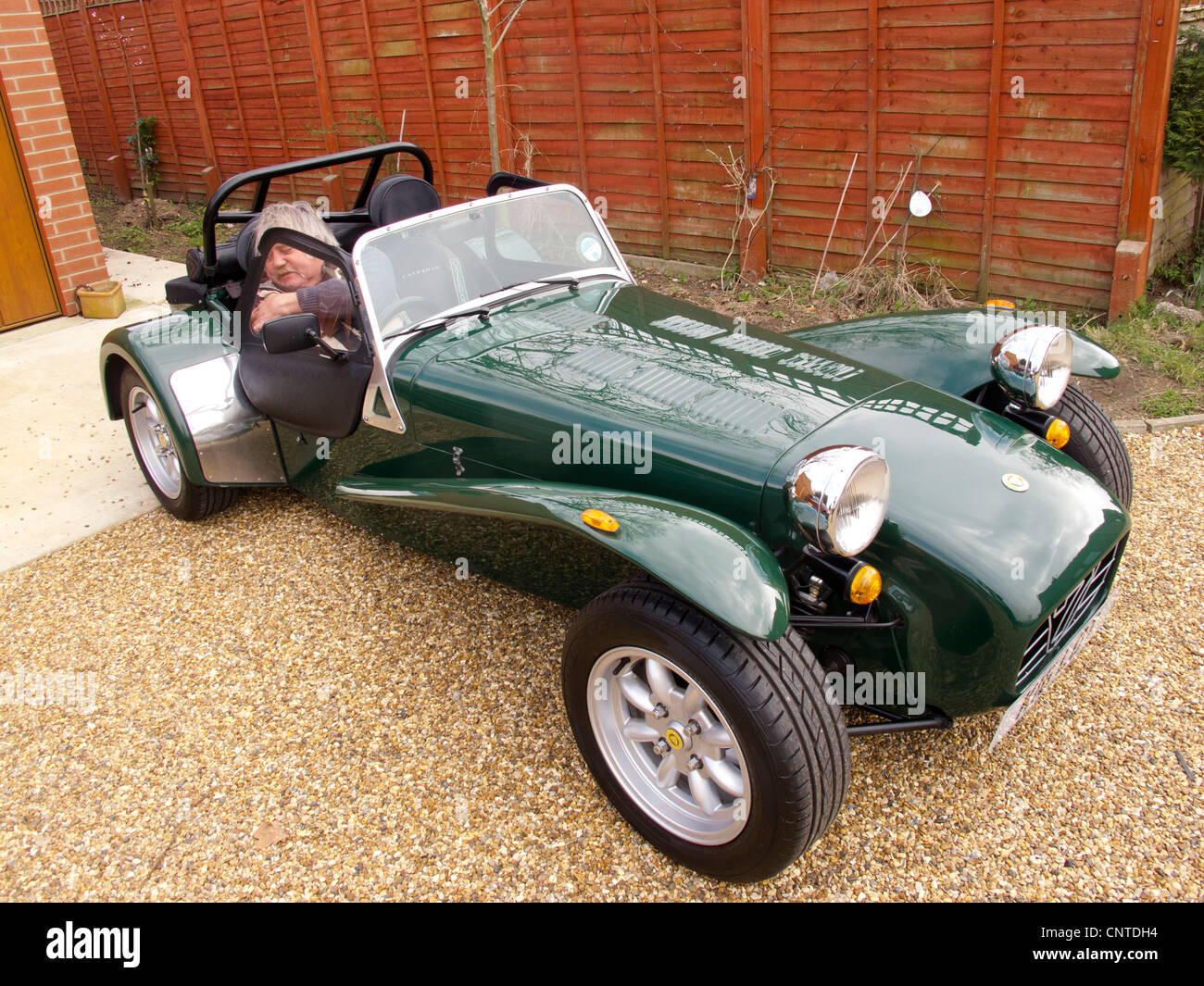 älterer Mann befestigt Sicherheitsgurt in British racing green Caterham sieben Sportwagen Stockfoto