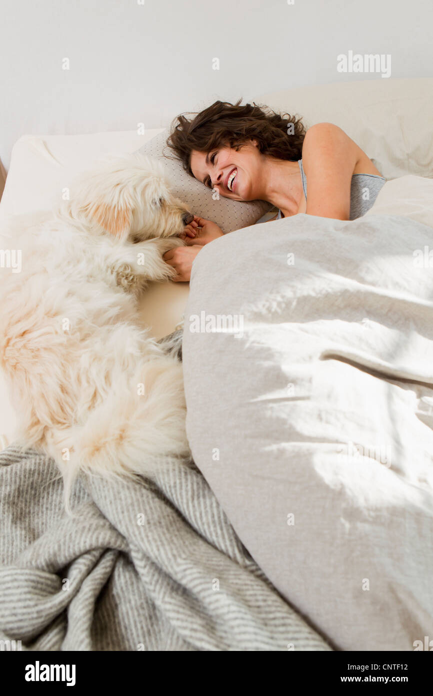 Frau mit Hund im Bett entspannen Stockfoto