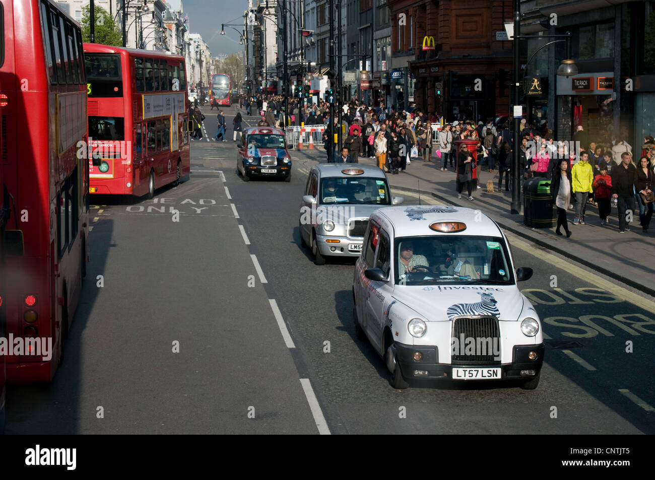 Taxis und Busse verlaufen entlang der Oxford Street, London. Die Bürgersteige sind voller Touristen und Shopper Stockfoto