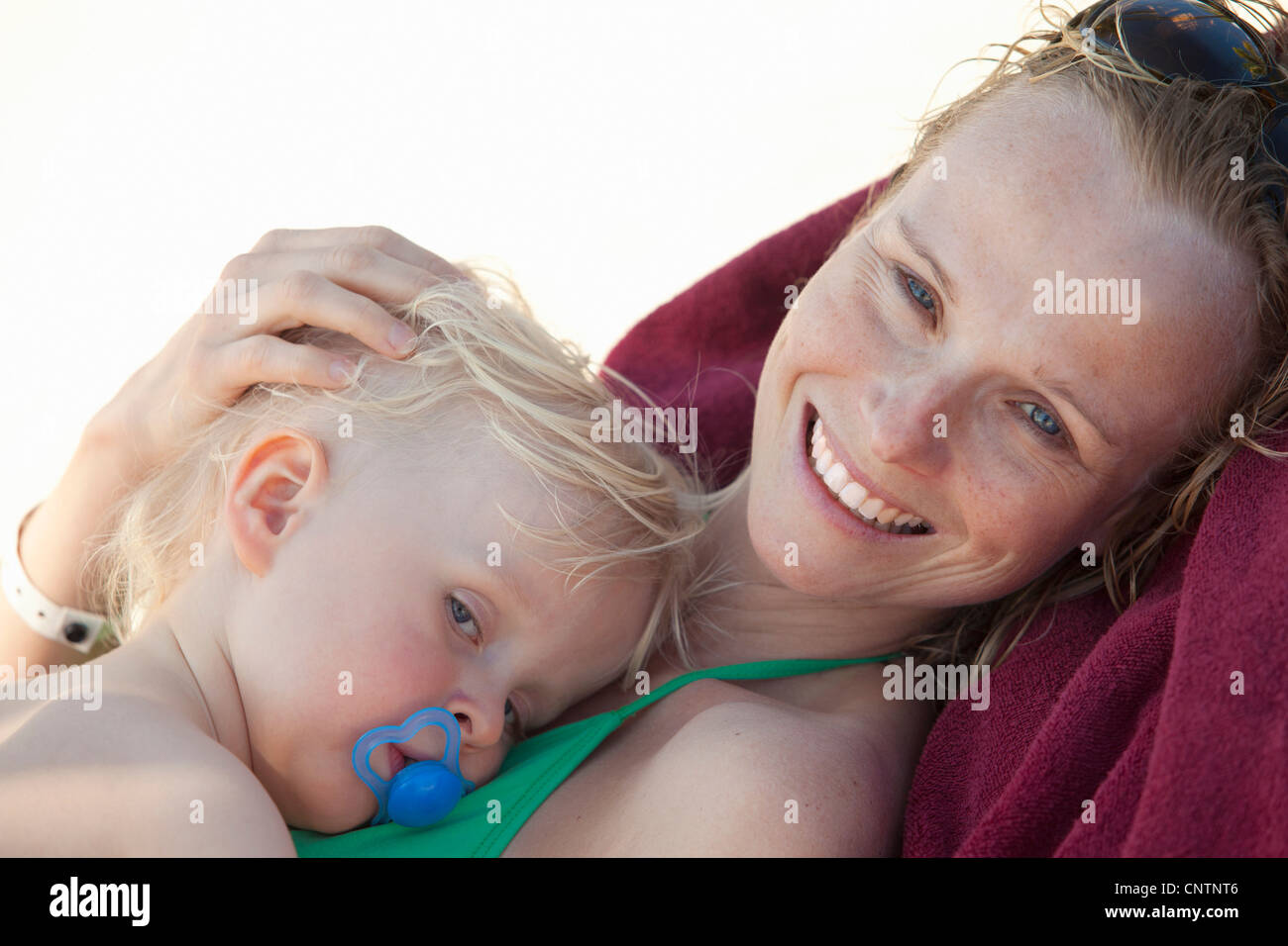 Lächelnde Frau kuscheln Baby am Strand Stockfoto