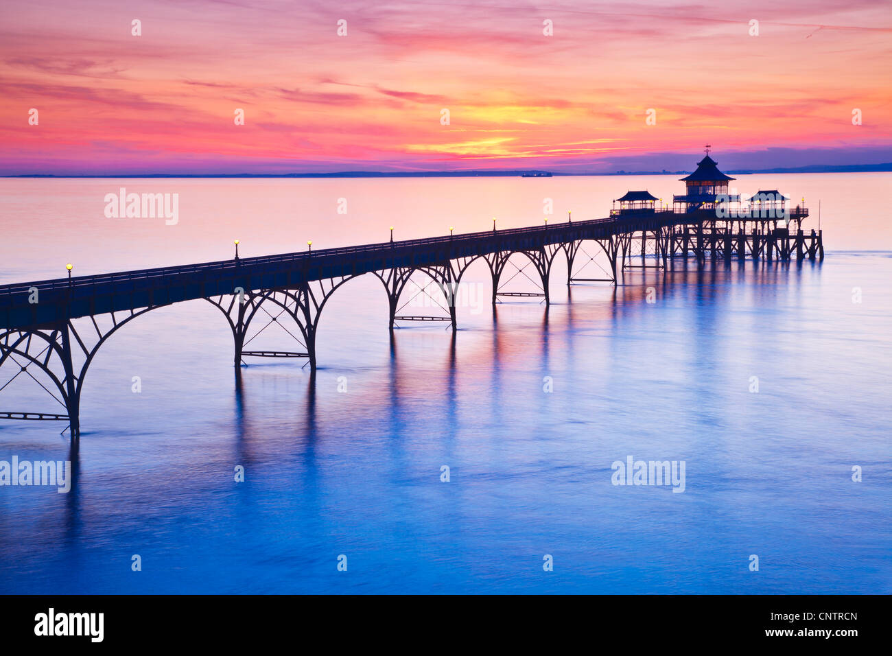 Die Sonne geht über den Bristolkanal hinter dem Pier in Clevedon, Somerset, England, UK Stockfoto