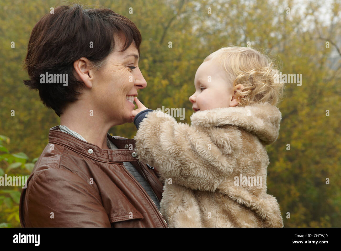 Lächelnde Mutter Holding Kleinkind im freien Stockfoto