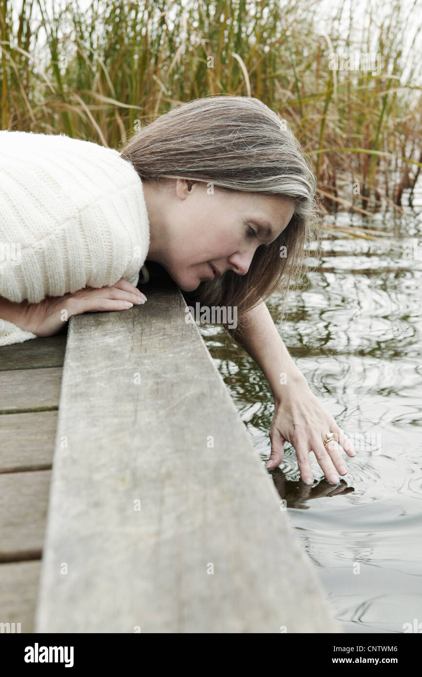 Ältere Frau Eintauchen der Finger in See Stockfoto