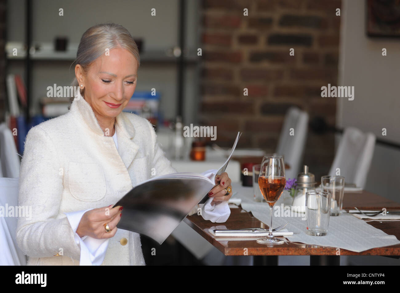 Ältere Frau liest Magazin im café Stockfoto