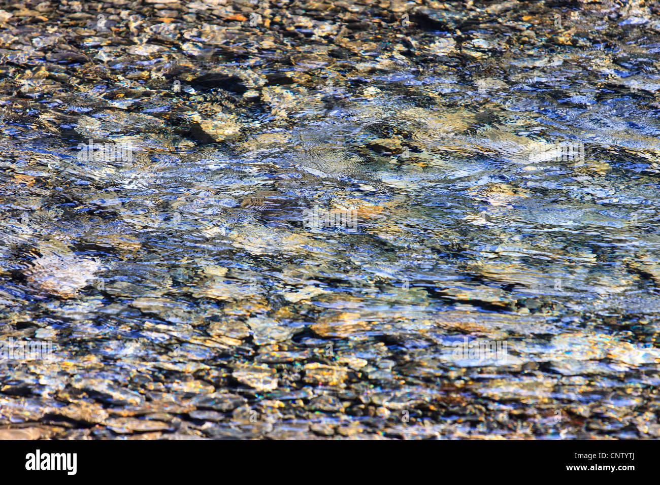 Kieselsteine unter Wasser, Wellen, Reflexion Stockfoto