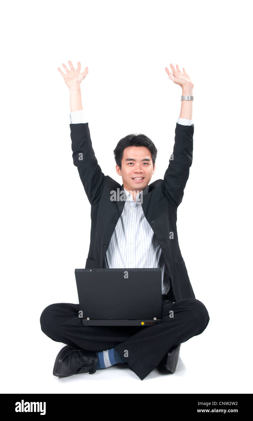 glückliche junge asiatische Geschäftsmann sitzen mit einem Laptop und rasing hand Stockfoto