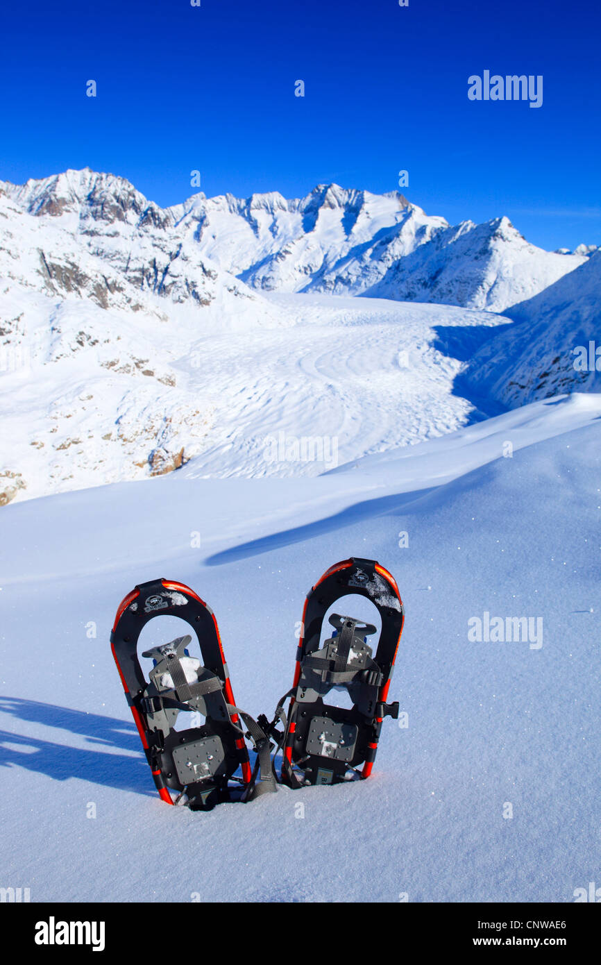 Paar Schneeschuhe stecken in einem unberührten Schneefeld in den Walliser Alpen vor winterlich verschneiten Wannenhorns und Aletschgletscher, Schweiz, Wallis Stockfoto