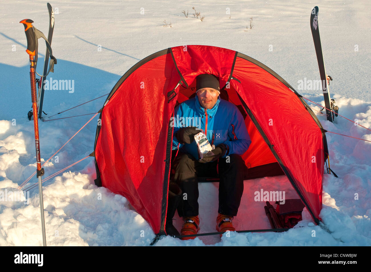 Skifahrer, die sitzen in seinem Lager gefriergetrocknetes Essen, Schweden, Lappland, Norrbotten, Sarek Nationalpark Stockfoto