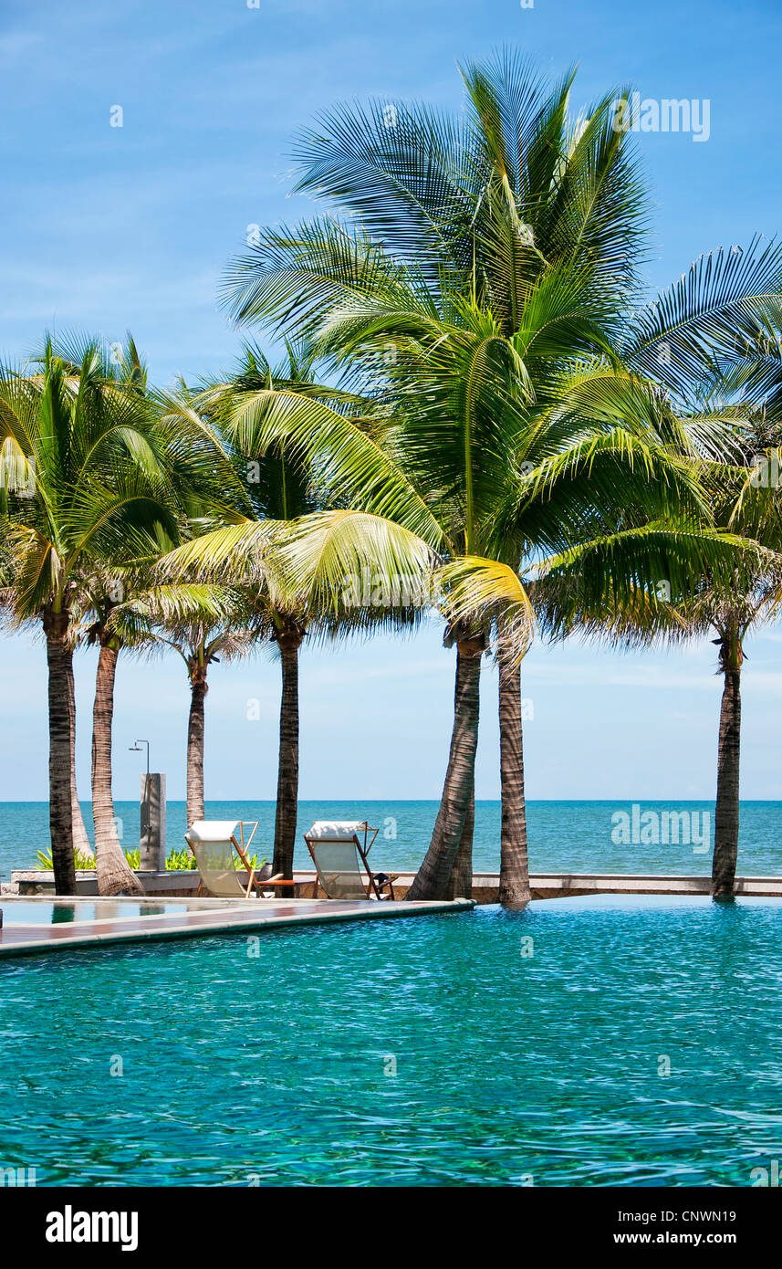 Ein Infinity-Hotelpool in Thailand mit einer Paradies-Kulisse von Palmen und das Meer. Stockfoto