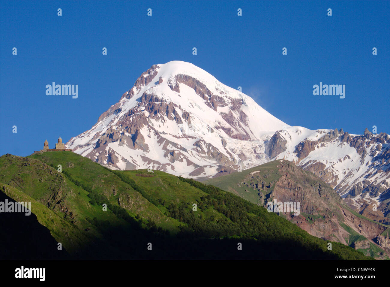 ruhender Schichtvulkan Kasbek (5,047 m), auf die Bergkette im Vordergrund der Kuppelkirche Tsiminda Sameba, Georgien, Mzcheta-Mtianeti, Qasbegi, Stepanzminda Stockfoto