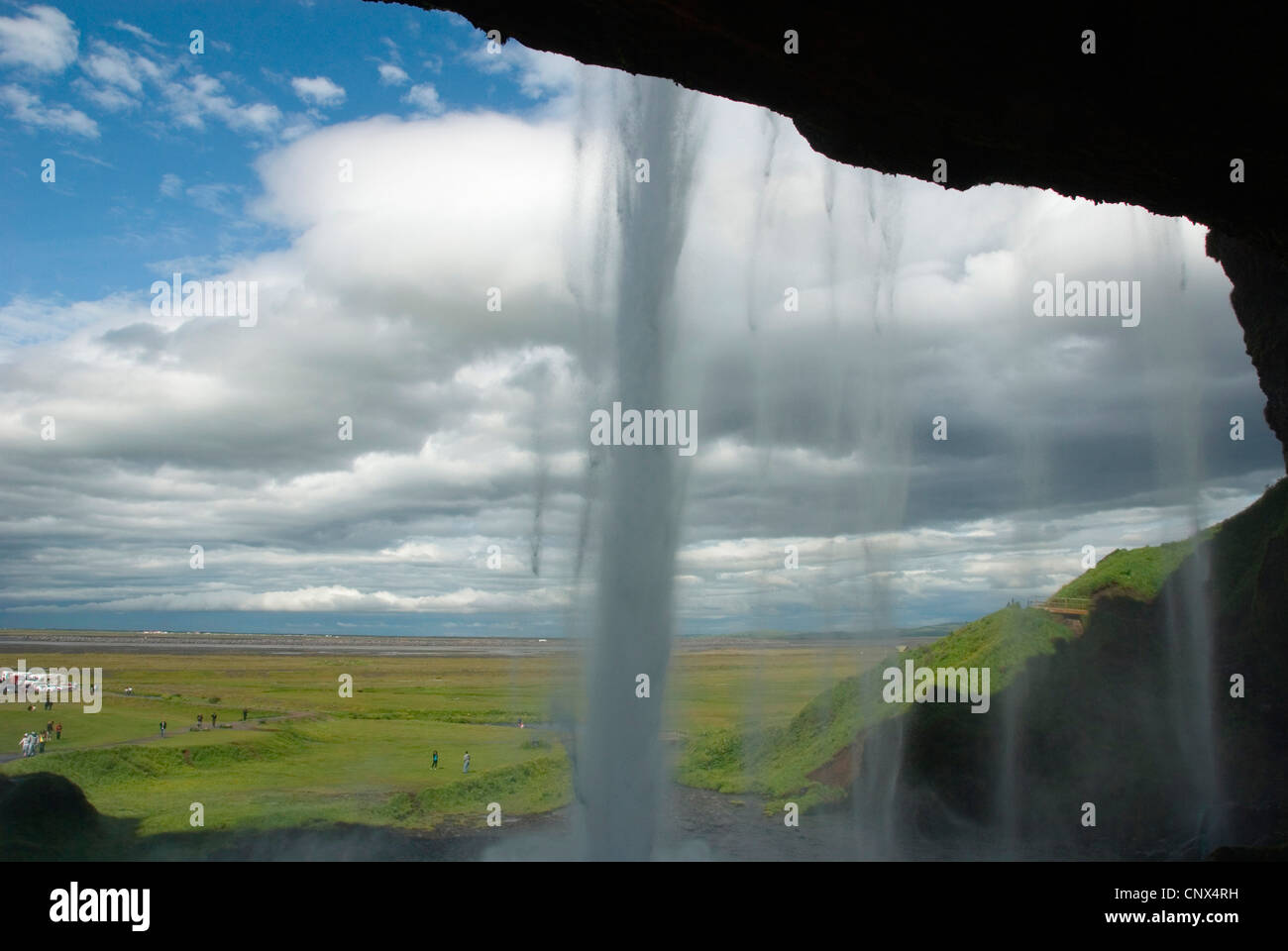 weite Ebene mit Touristen gesehen hinter dem Wasserfall Seljalandsfoss des Flusses Seljalandsa, Island Stockfoto