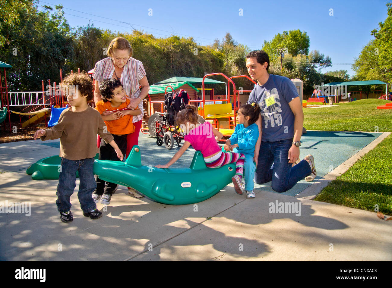 Jung und alt Mitarbeiter helfen blinden und verkrüppelt Nutzung durch Kinder den Spielplatz an der blinde Kinder Learning Center. Stockfoto