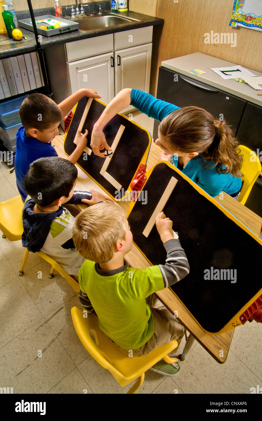 Ein Lehrer beobachtet, wie blinde jungen den Buchstaben "L bilden" durch Berührung mit zwei Stöcken eine in einem speziellen Pre-Braille schreiben Klasse braucht. Stockfoto